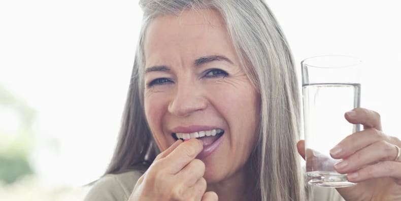 woman taking multivitamin with water