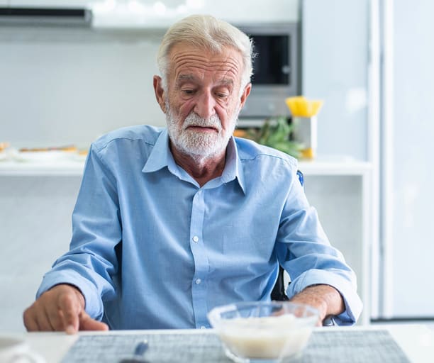 senior man sat at table appetite loss