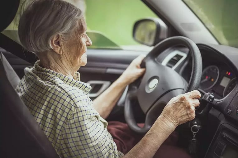 senior behind steering wheel